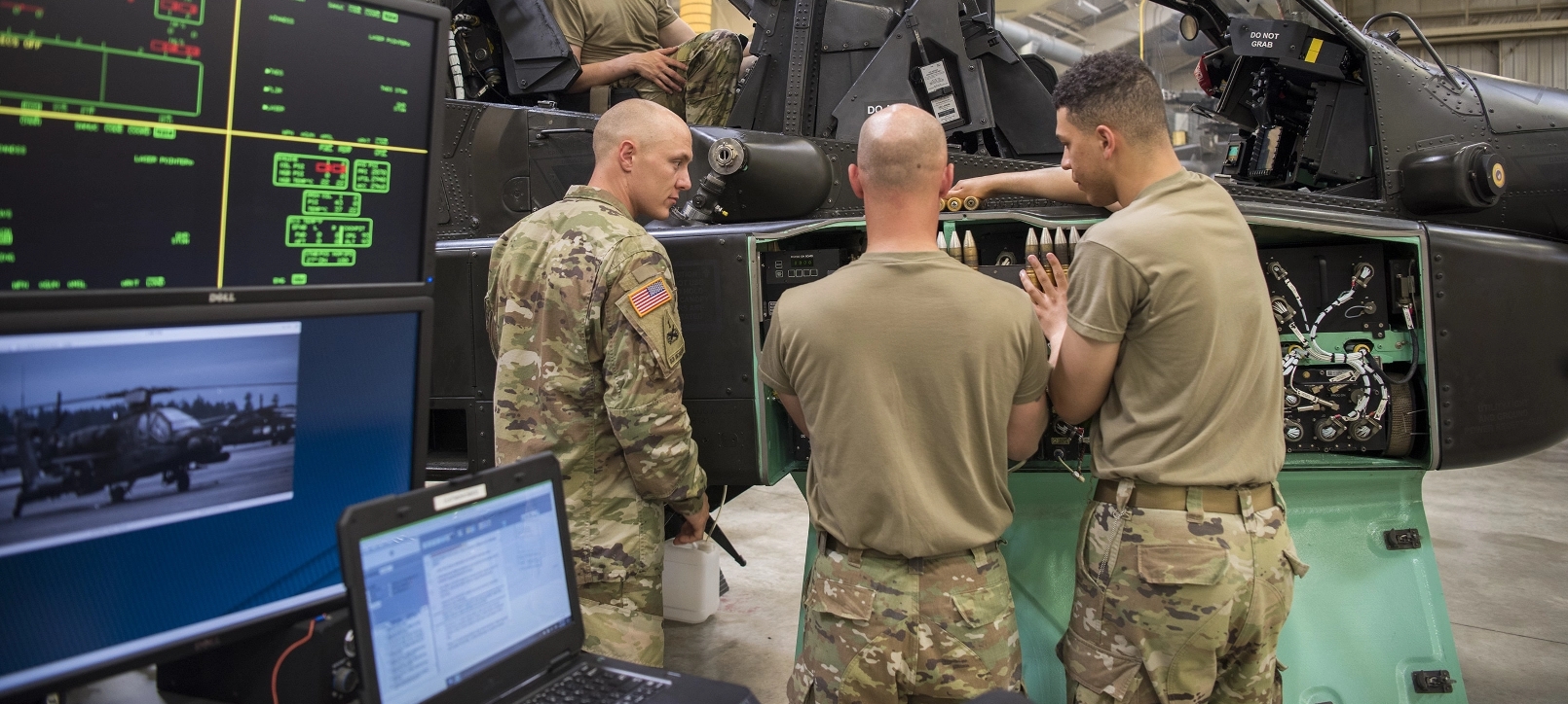 Three soldiers loading ammunition into a military helicopter