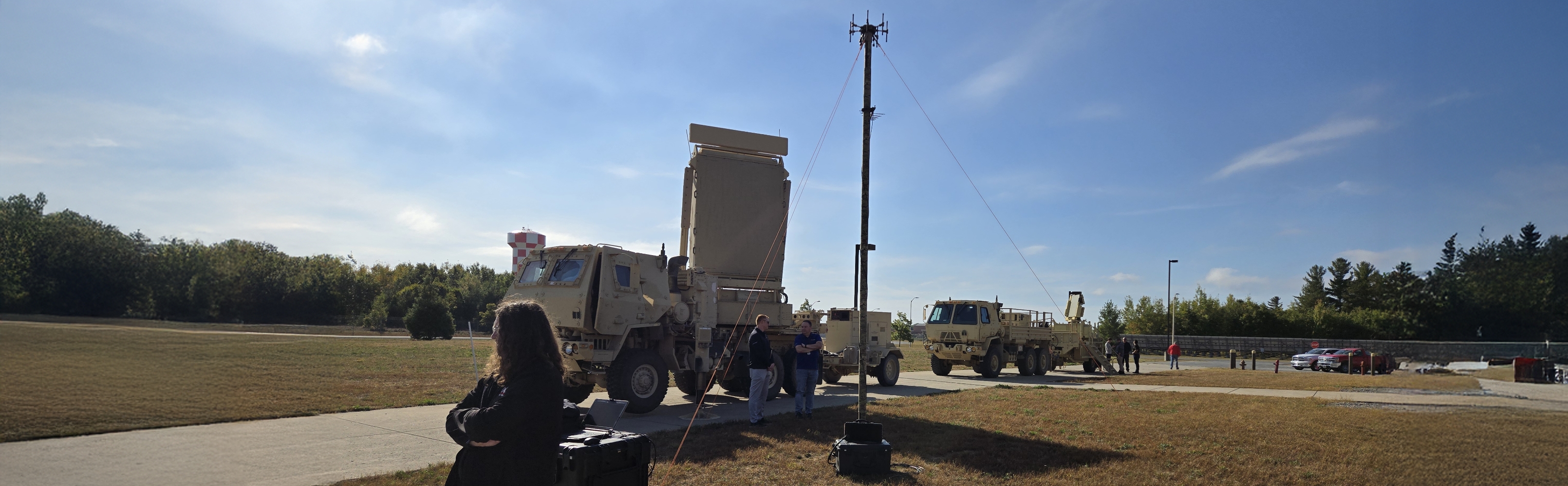 A group of people gathered around a large military vehicle, discussing its features and specifications.