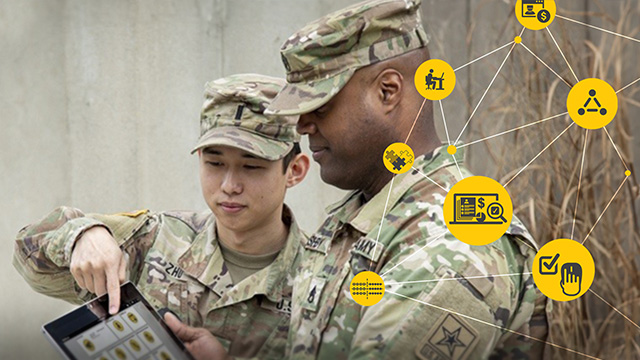 Two soldiers in camouflage uniforms look at a tablet.