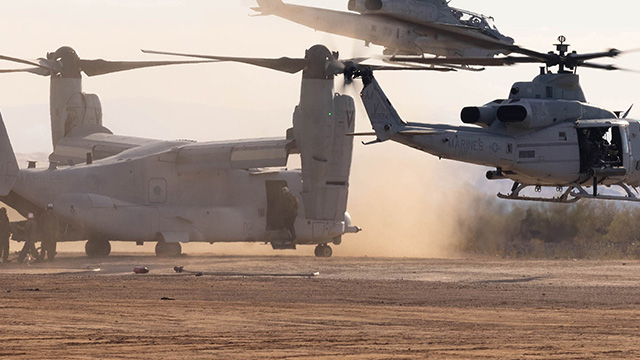 Military aircraft perform landing maneuvers on a dusty field.