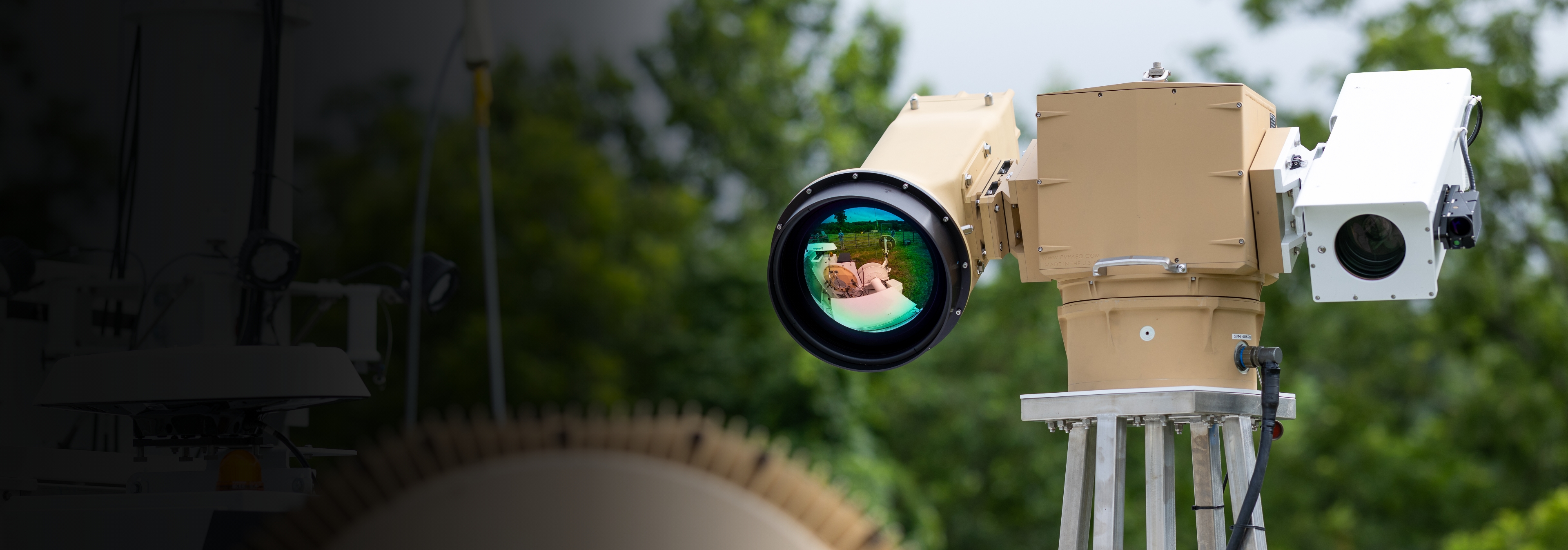 A camera mounted on a pole with a tree in the background, capturing the surrounding environment.