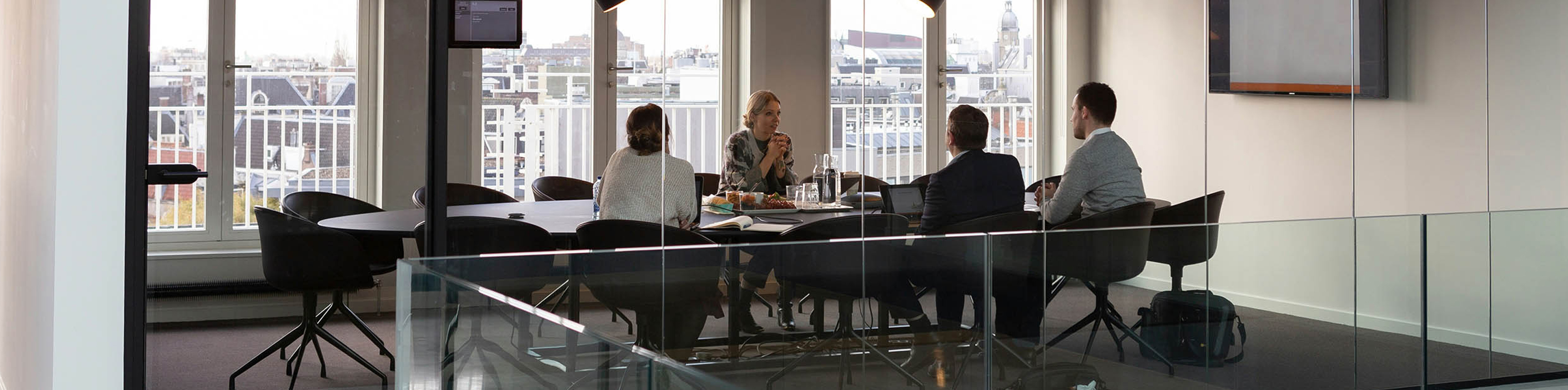 A glass railing with a table and chairs positioned in front of a large window, allowing natural light to enter the space.