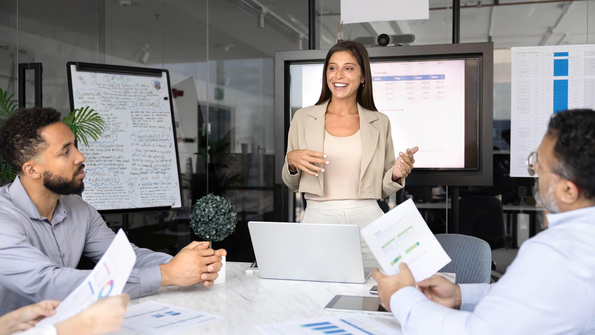 A woman presents to her colleagues in a conference room, engaging them with her ideas and visuals.