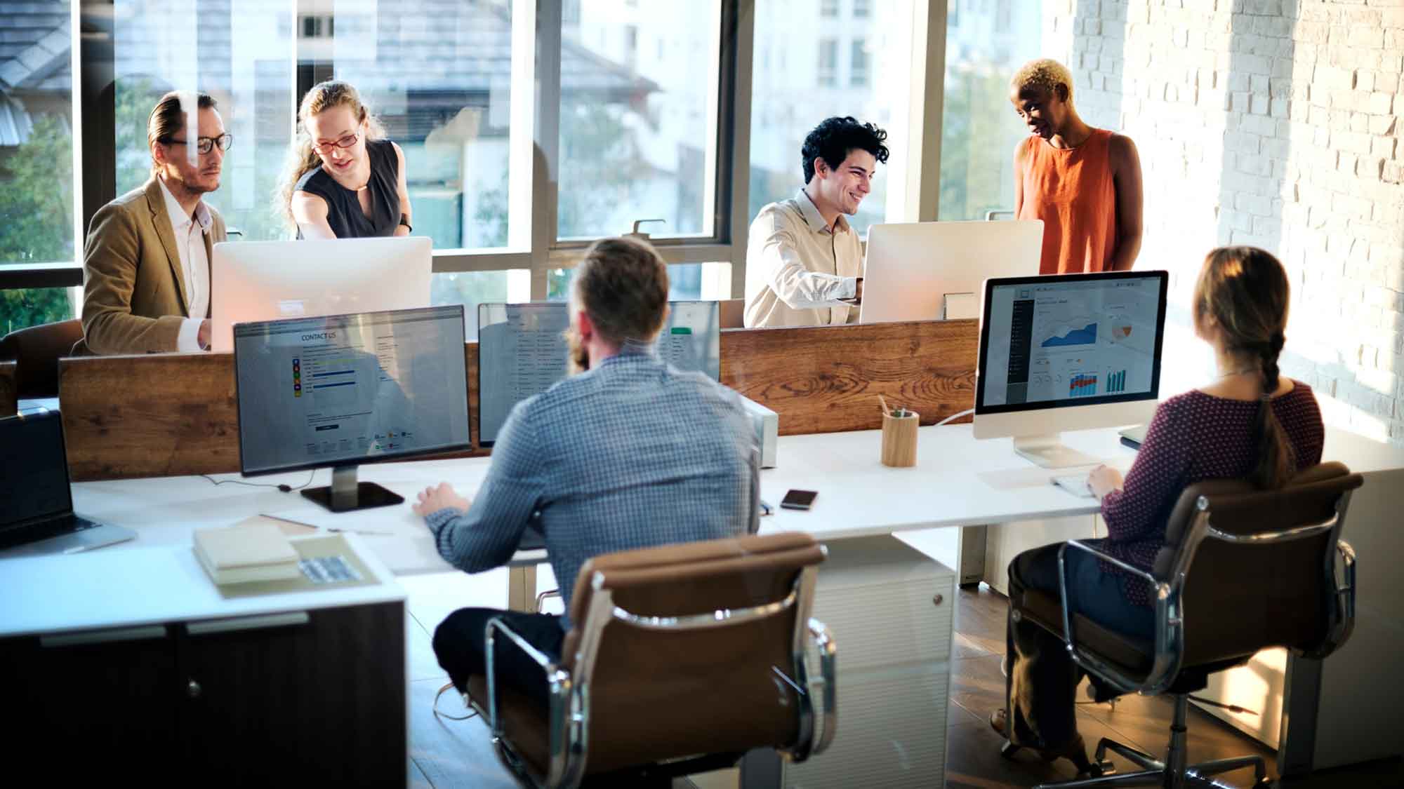 A group of professionals collaborating at a desk in a modern office environment.