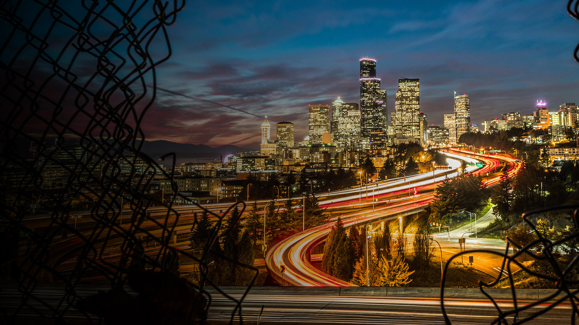 A vibrant cityscape featuring traffic lights and a skyline of tall buildings under a clear blue sky.