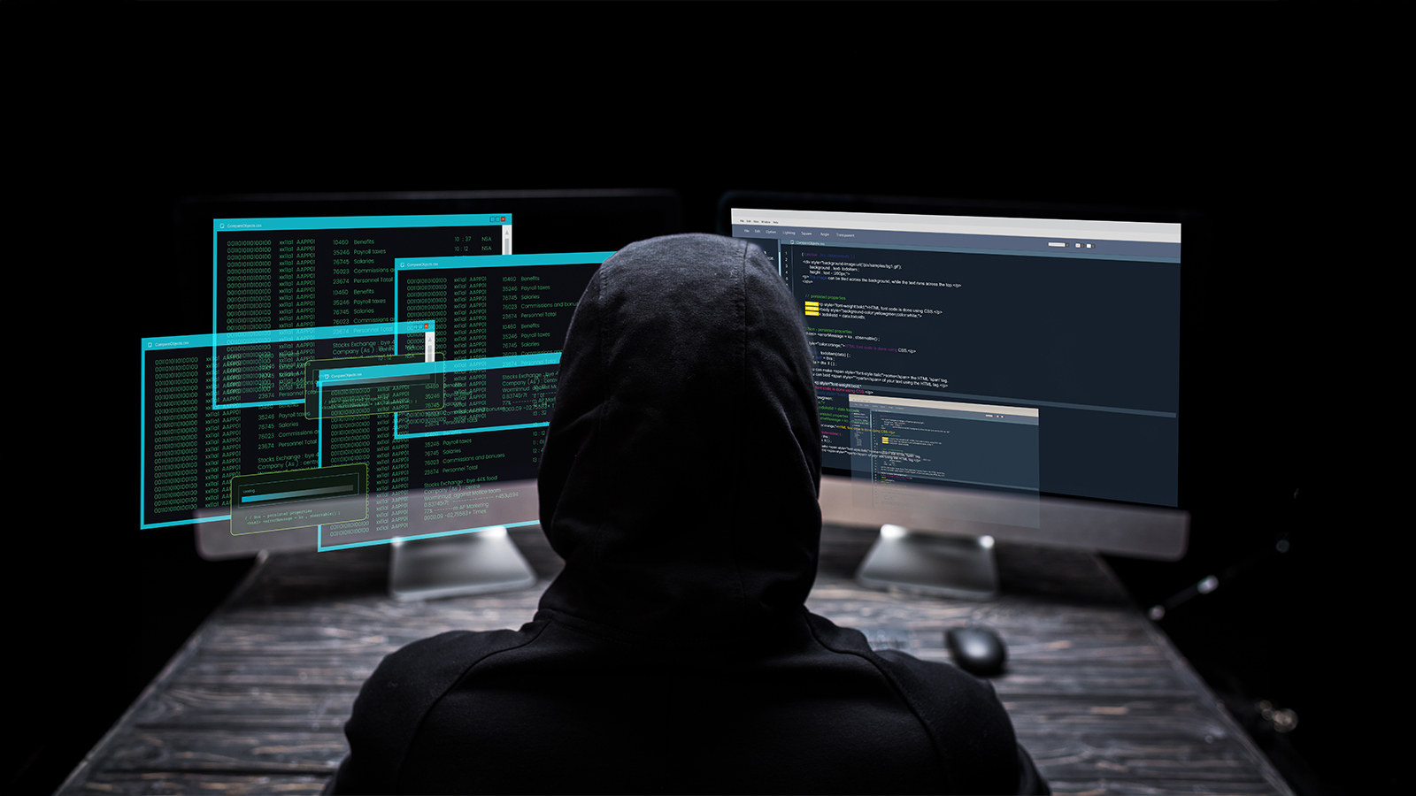 A person in a hoodie sits at a computer, focused on the screen, with a neutral background.