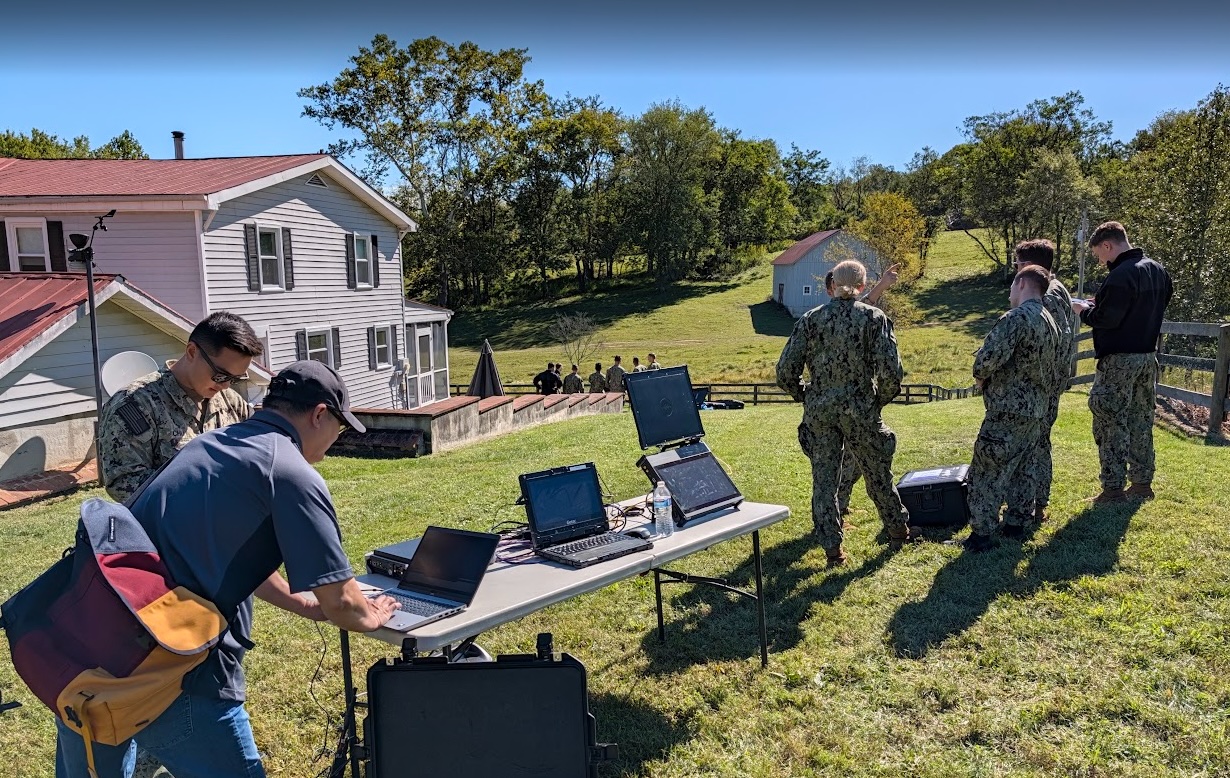 CACI engineers walk midshipmen through real-time signal analysis and system operations at a training station.