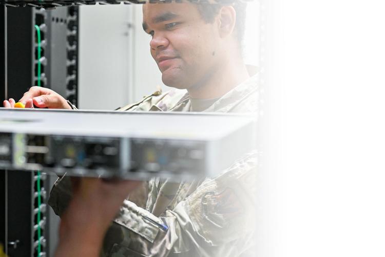 Two soldiers standing together installing a server rack.