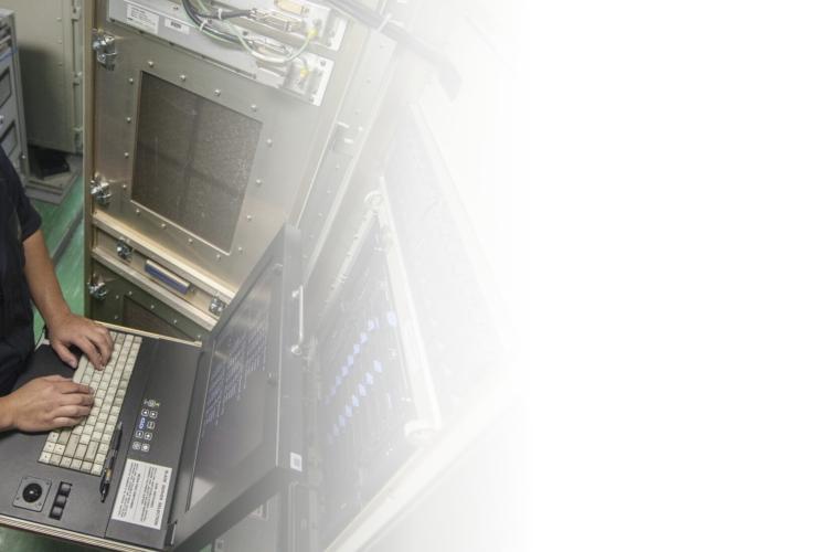 A woman in a navy uniform focused on her laptop, engaged in work with a professional demeanor.