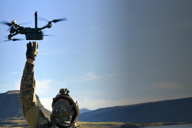A person stands holding a drone above a statue, capturing a unique aerial perspective of the artwork below.