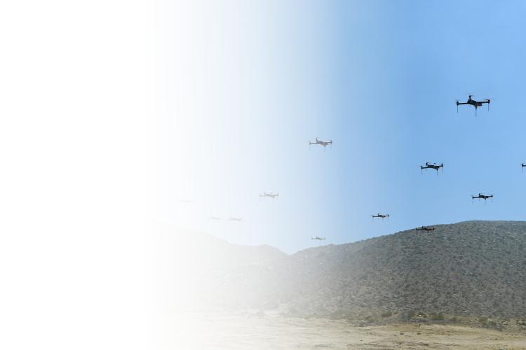 A group of drones flying in a precise formation against a clear blue sky.