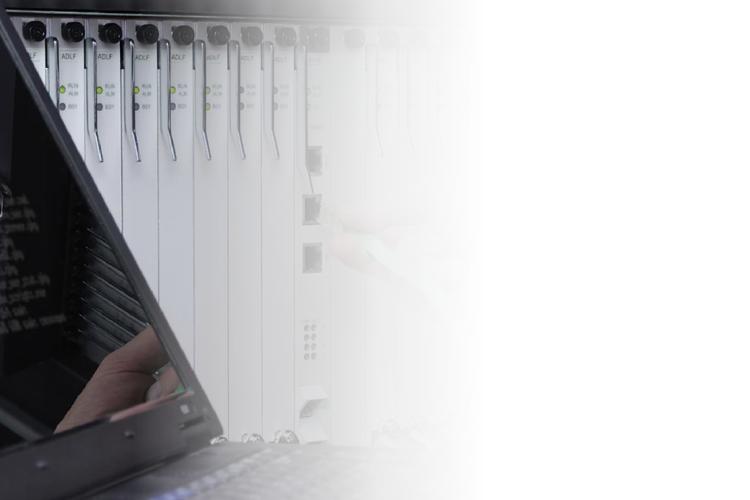 A laptop on a desk beside a rack of servers, illustrating a tech workspace setup.