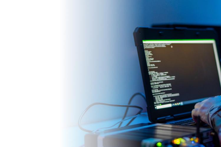 A person working on a laptop in front of a larger monitor, focused on their tasks.