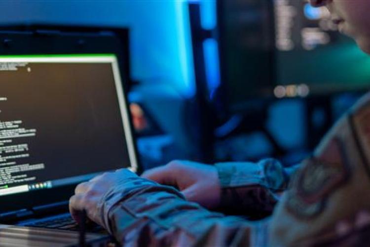 A soldier focused on a laptop computer, engaged in work or communication.