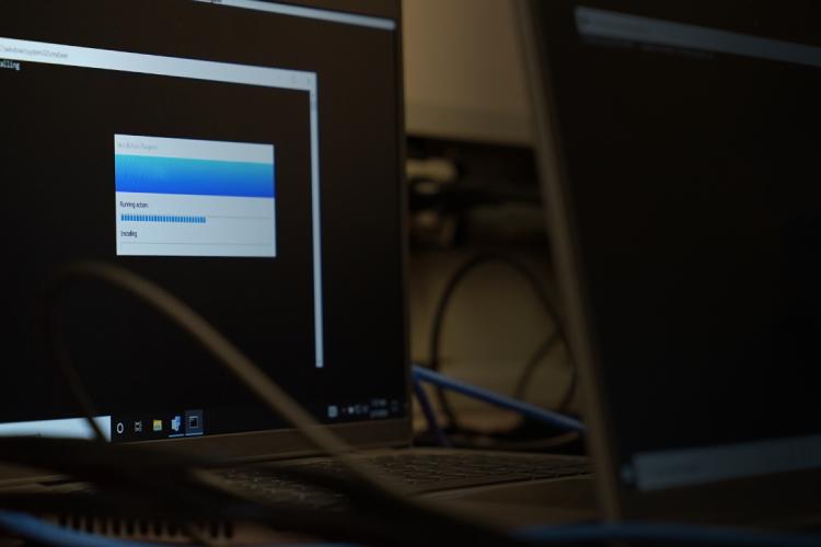 Two laptops on a desk surrounded by various wires, showcasing a workspace setup.