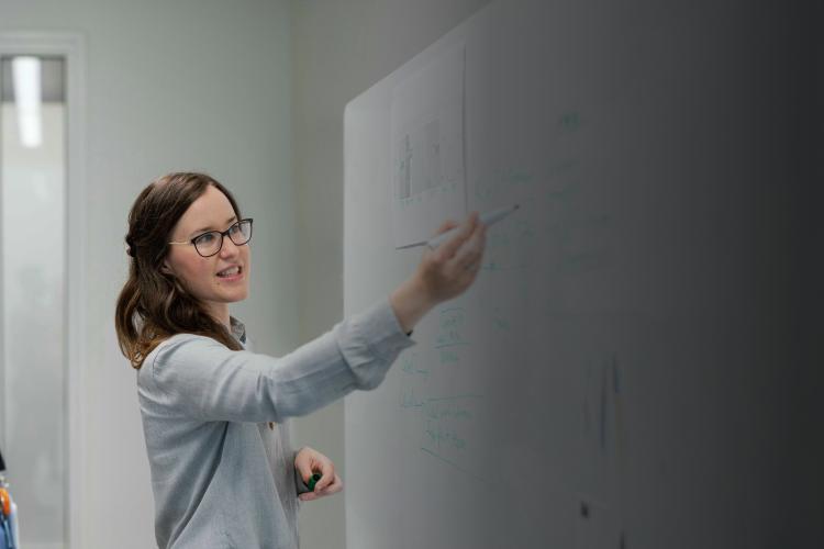 Two individuals standing in front of a whiteboard, engaged in discussion or presentation.