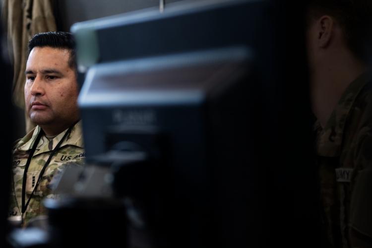 A soldier intently observes a computer screen, focused on the task at hand.