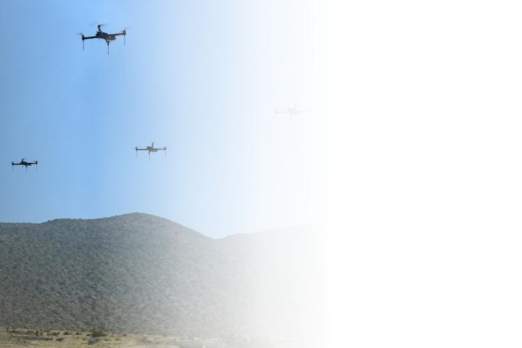 A  group of drones flying in a precise formation against a clear blue sky.