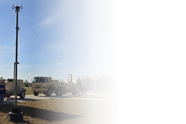 A group of people gathered around a large military vehicle, discussing its features and specifications.