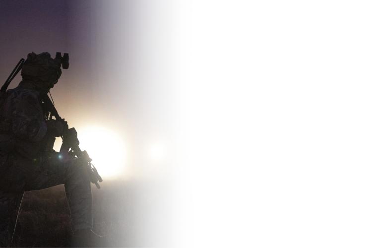 A dark silhouette of a man holding a rifle, set against a shadowy background.