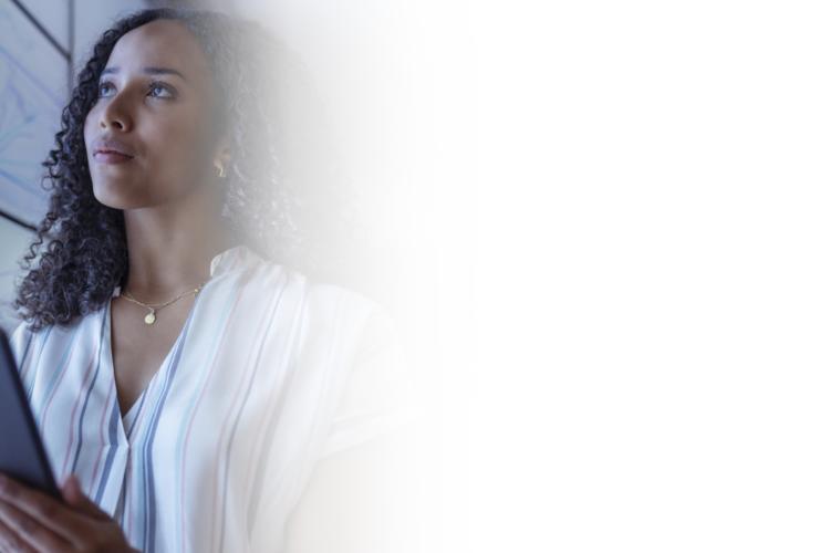 A woman stands holding a tablet in front of a whiteboard, engaged in a presentation or discussion.
