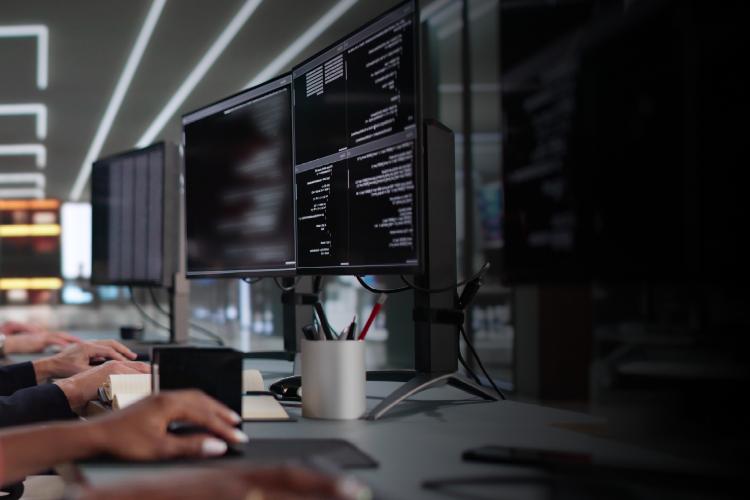 Two women collaborating on computers in a modern office setting, focused on their work.