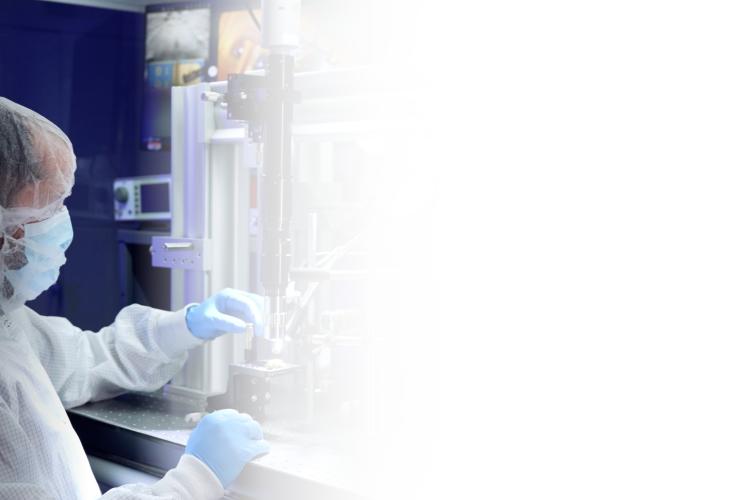 A man in a lab coat operates a complex machine in a laboratory setting, focused on his task.