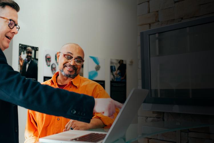 Two men shaking hands in front of a laptop, symbolizing a successful business agreement or partnership.
