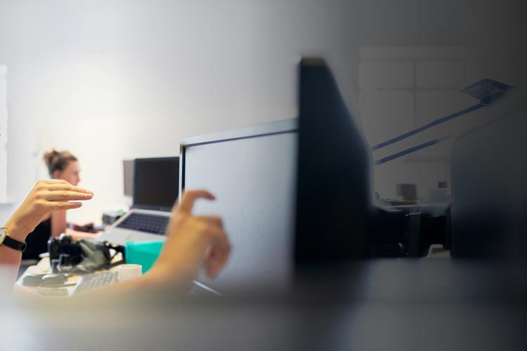 Two individuals are focused on a computer screen, engaged in discussion or analysis of the displayed content.