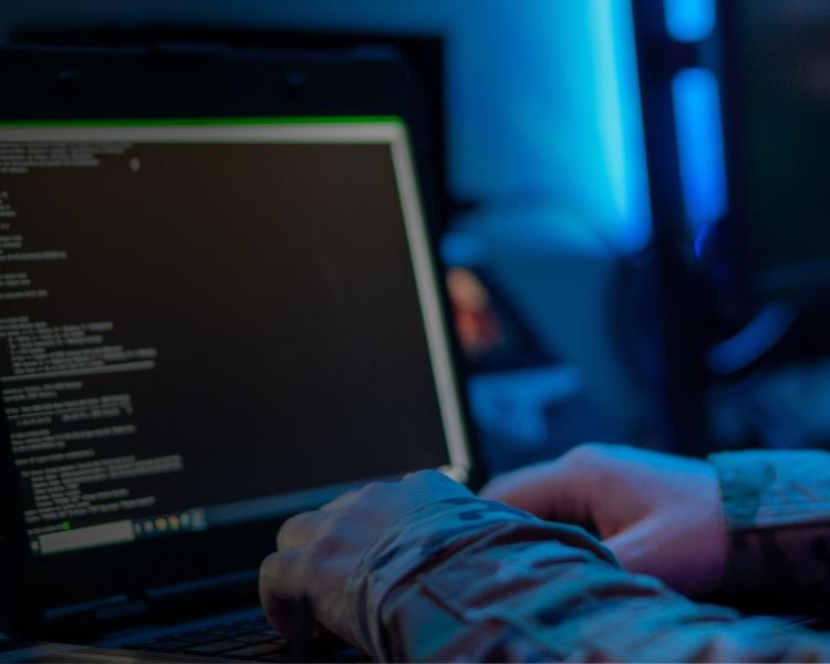 A person focused on typing on a laptop computer, with hands positioned over the keyboard.