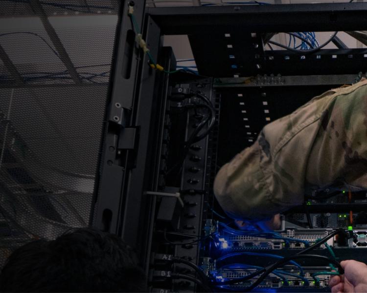 A soldier in uniform focused on a computer, demonstrating dedication and professionalism in a military setting.
