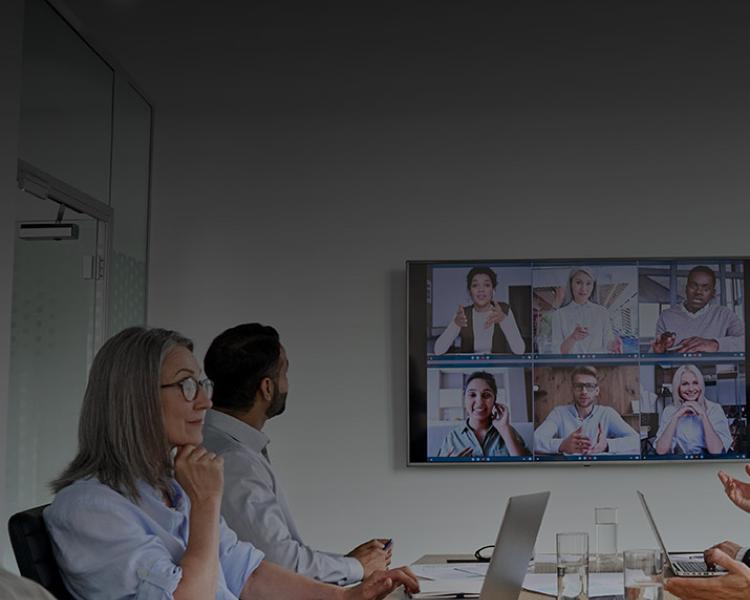 A diverse group of professionals engaged in a video conference in a modern meeting room.