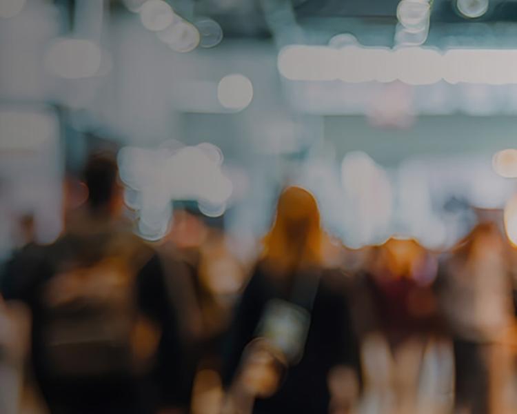 Blurry image of people walking through a spacious room, creating a sense of movement and activity.