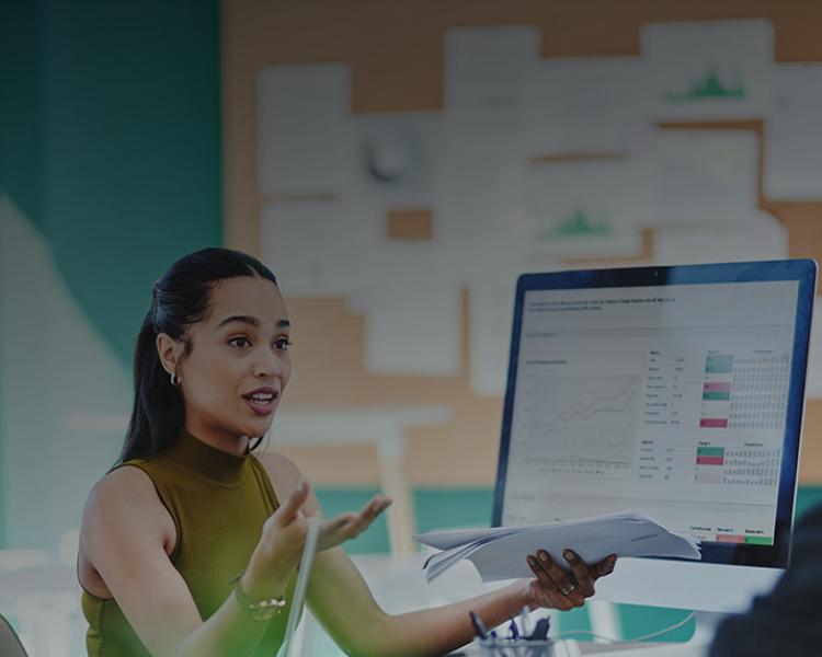 A group of five people gathered around a table, focused on a computer screen displaying information.