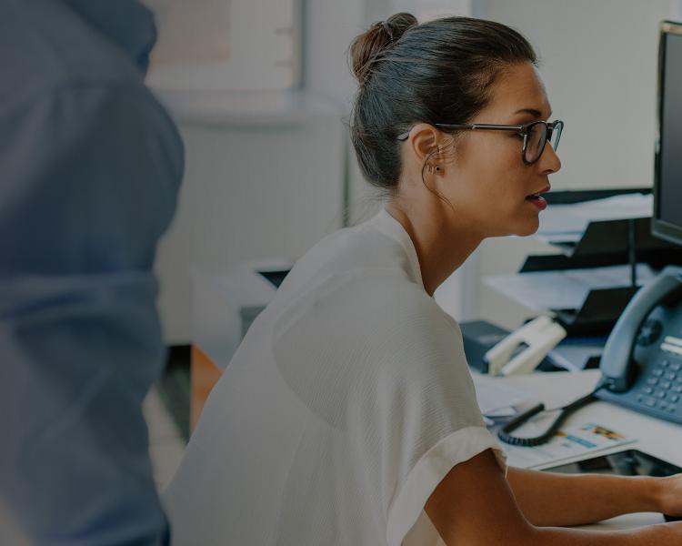 A woman focused on her computer while working in a modern office environment.