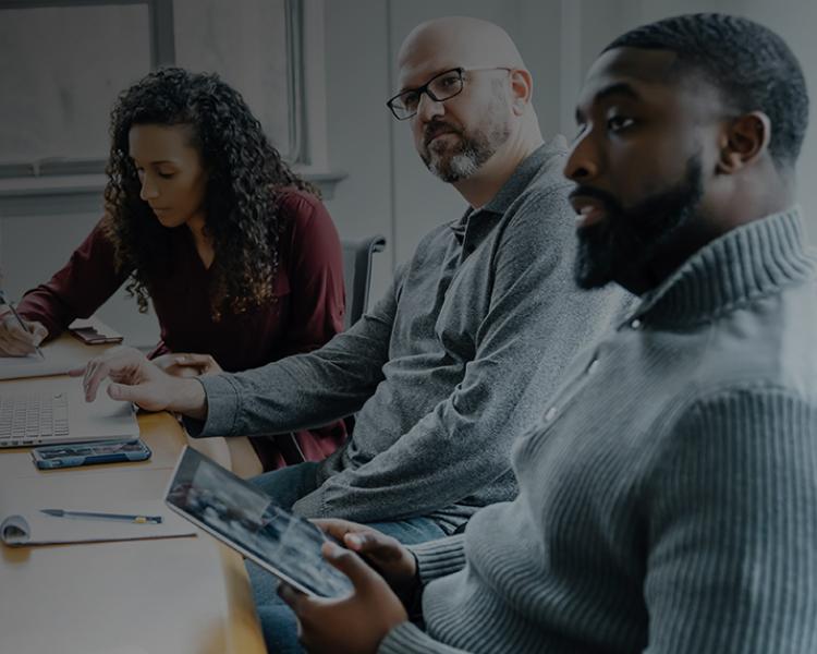 A group of people collaborating around a table, each using a laptop for discussion and teamwork.
