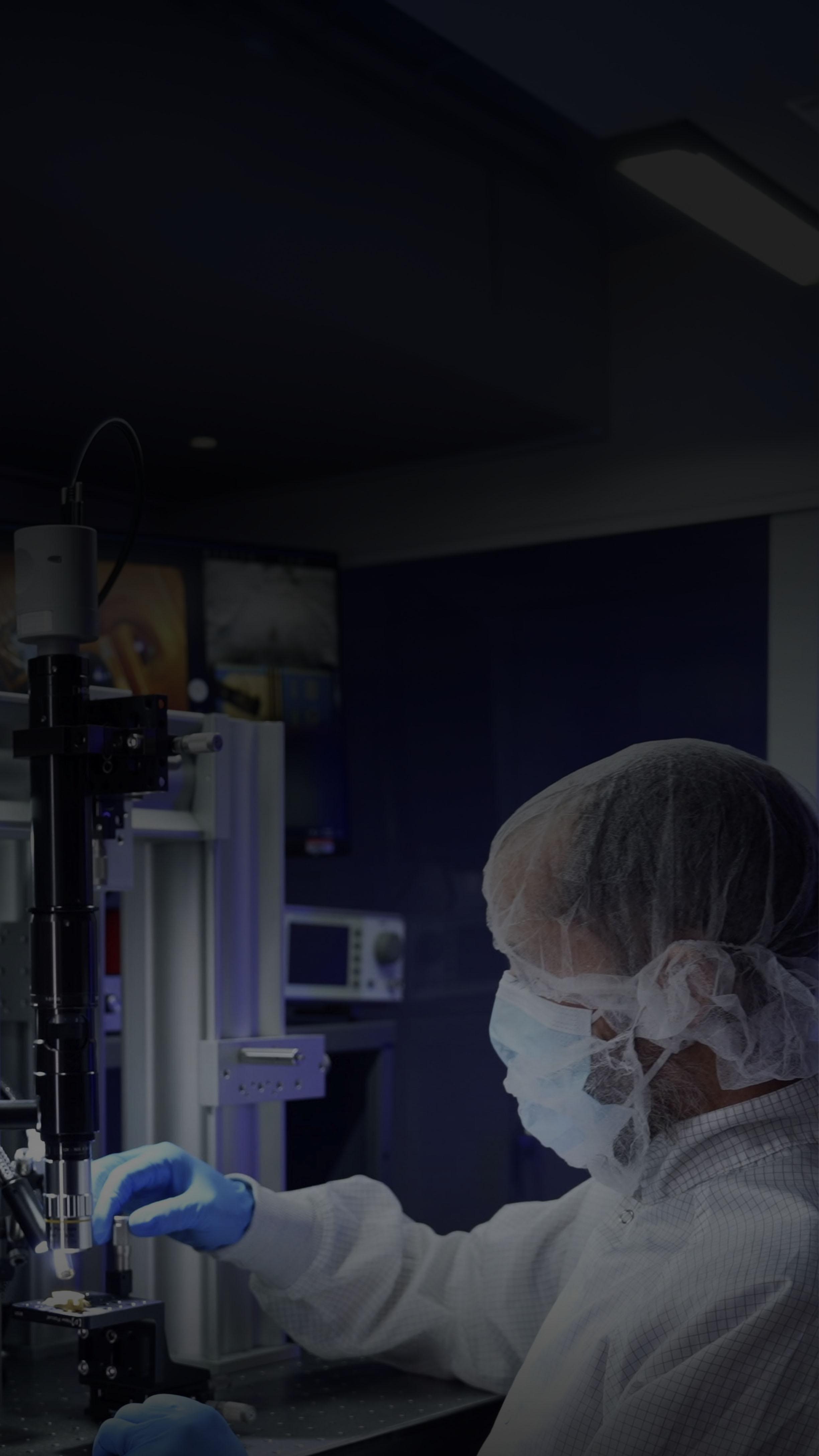 A person in a lab coat operates a complex machine, focused on their task in a laboratory setting.