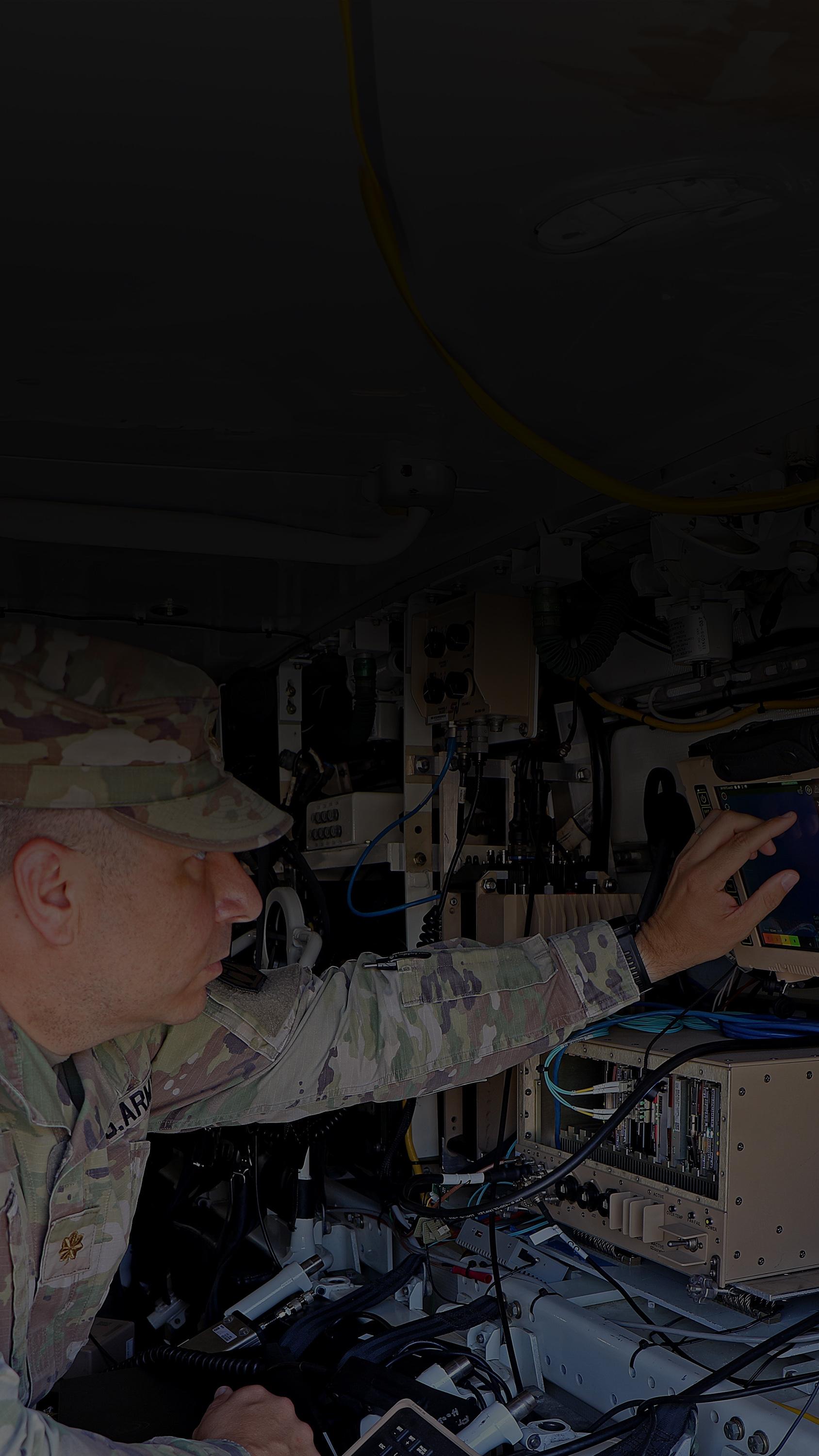 A soldier focused on a laptop computer, engaged in work while in a military setting.