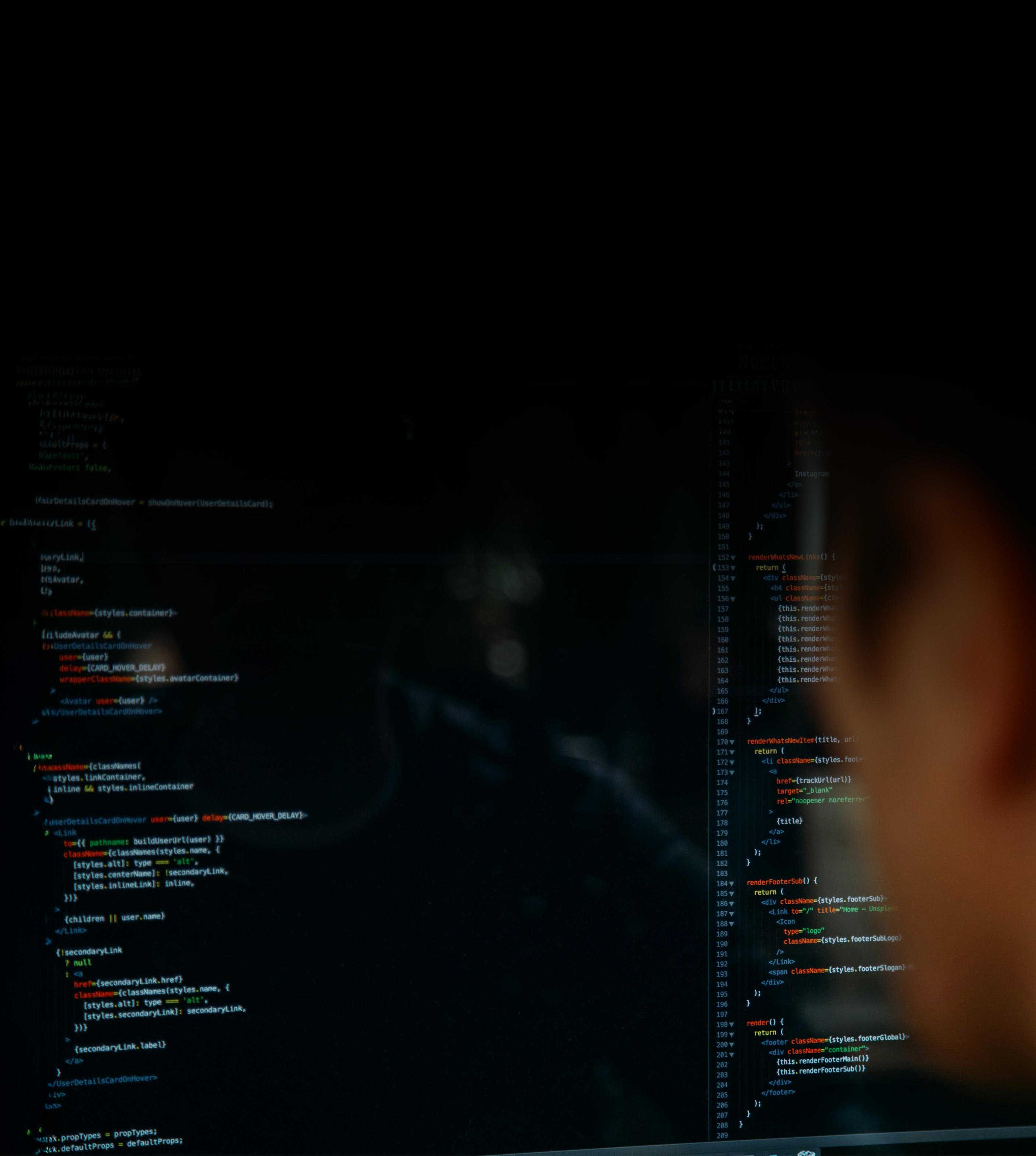 A person intently gazes at a computer screen displaying lines of code.
