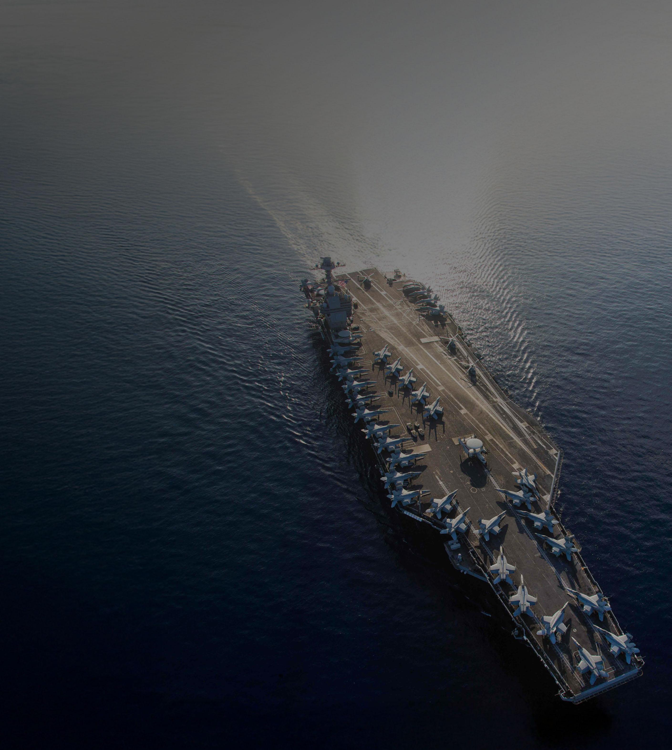 Aerial view of the USS CVN-76 aircraft carrier, showcasing its deck and surrounding water.