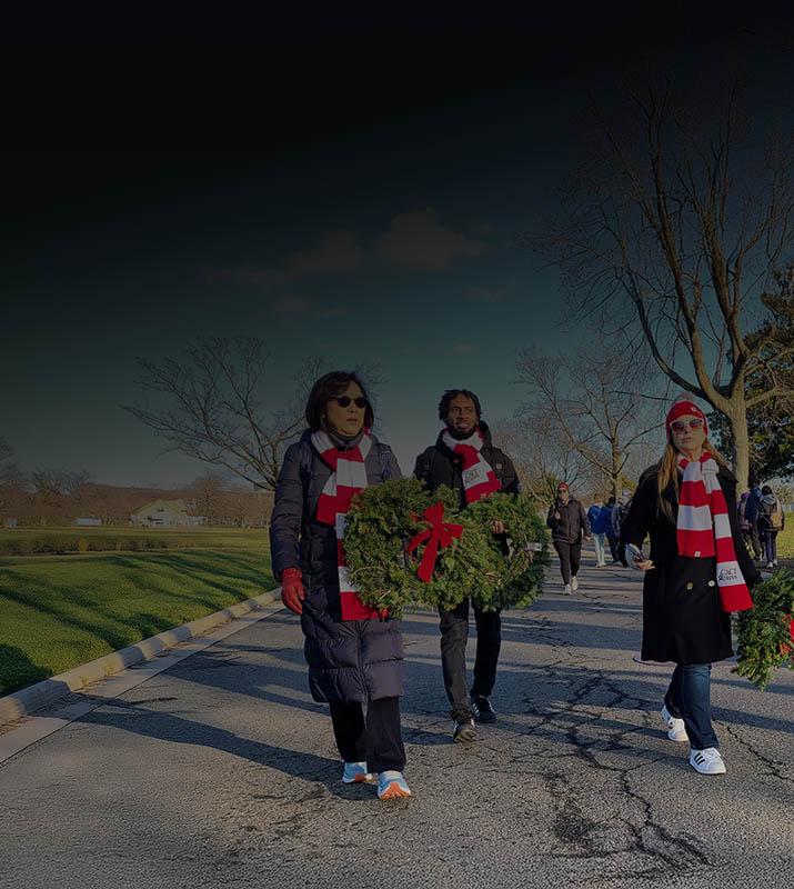 A group of people walking down a road, each carrying a decorative wreath in their hands.