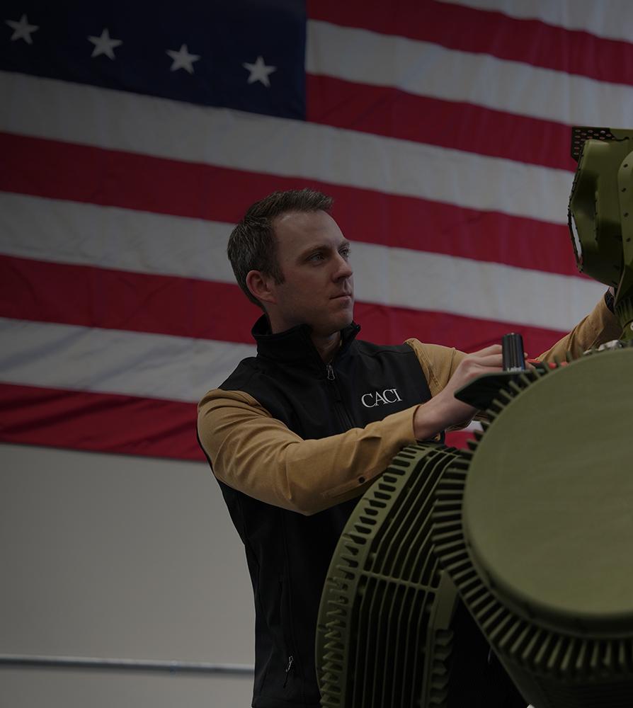 A man is assembling a large green robot, focused on its intricate mechanical components.
