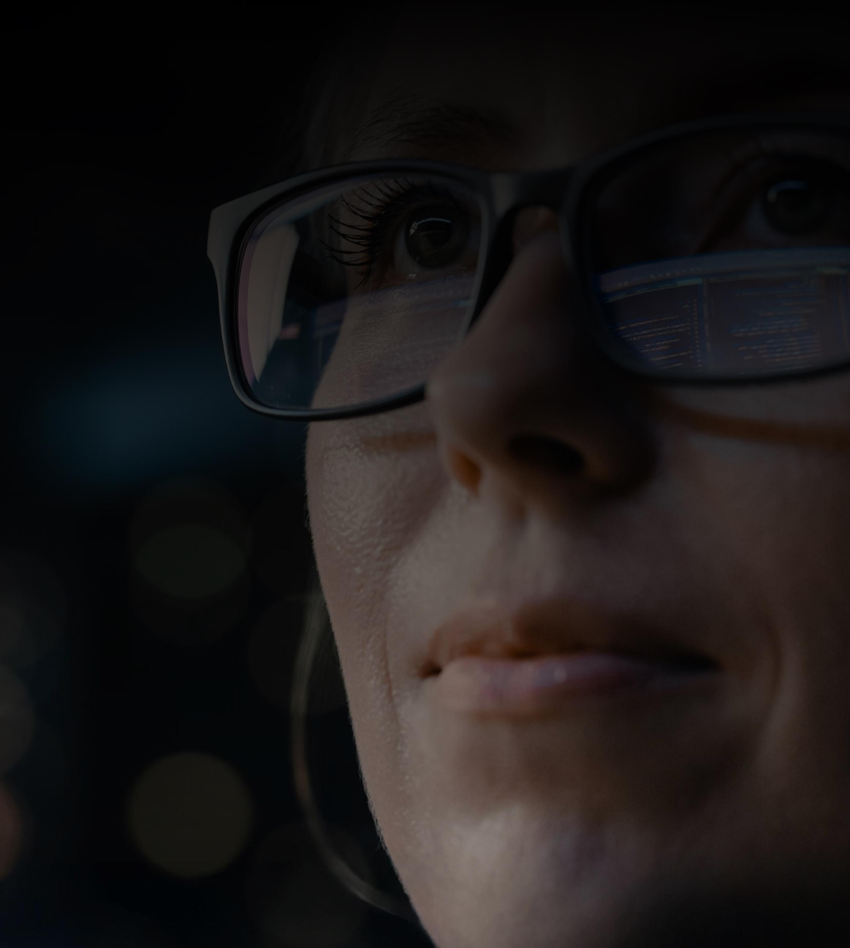 A woman with glasses gazes thoughtfully to the side, her expression contemplative and focused.
