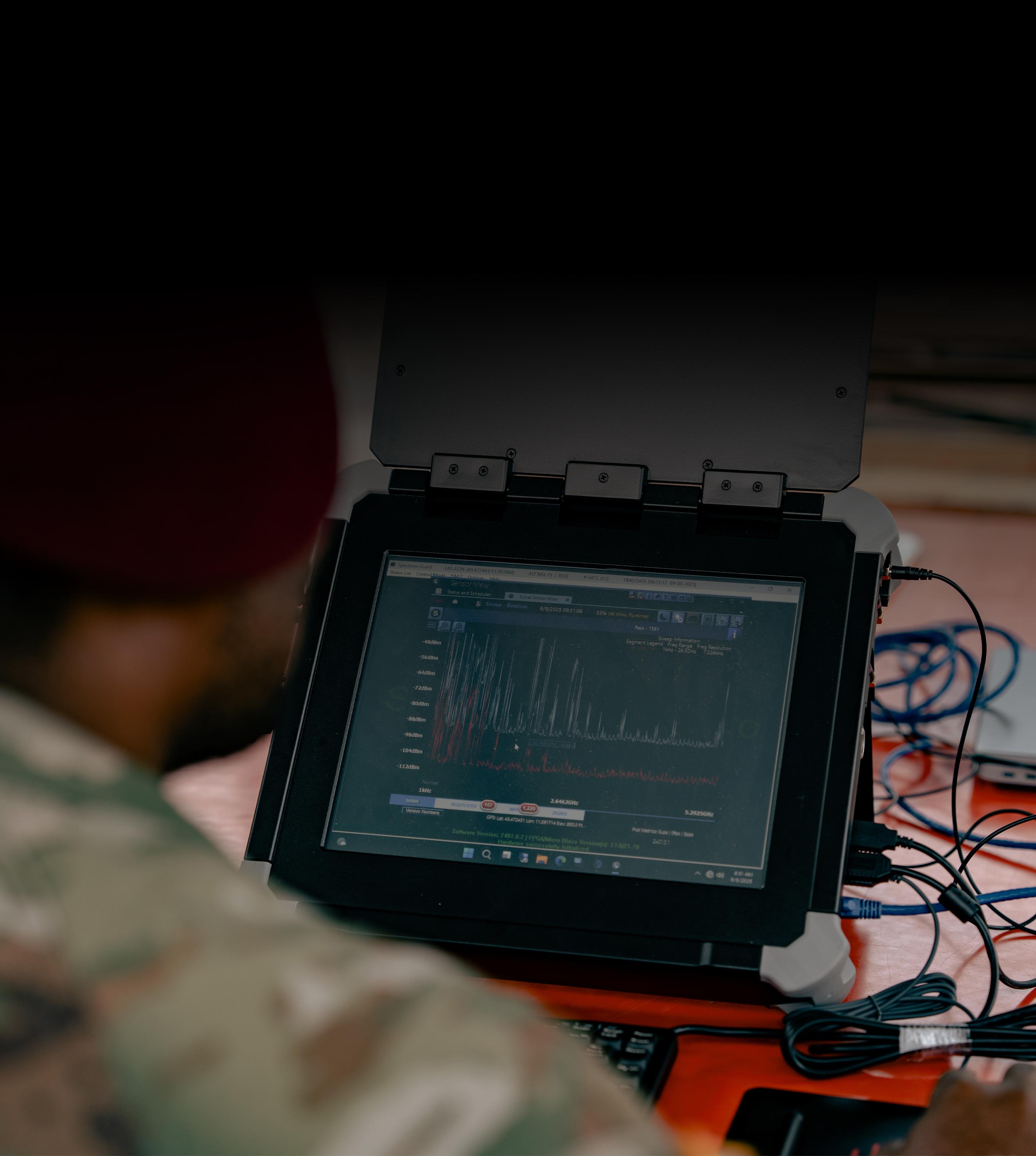 A soldier focused on a laptop computer, engaged in work or communication.