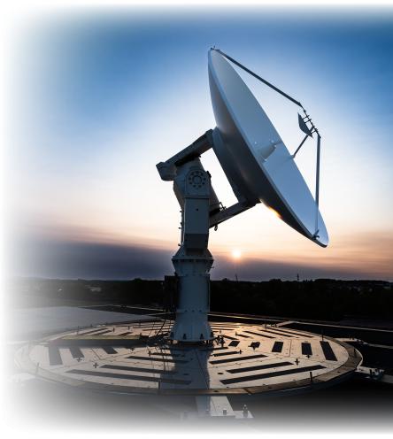 Large satellite dish on a platform at sunset.