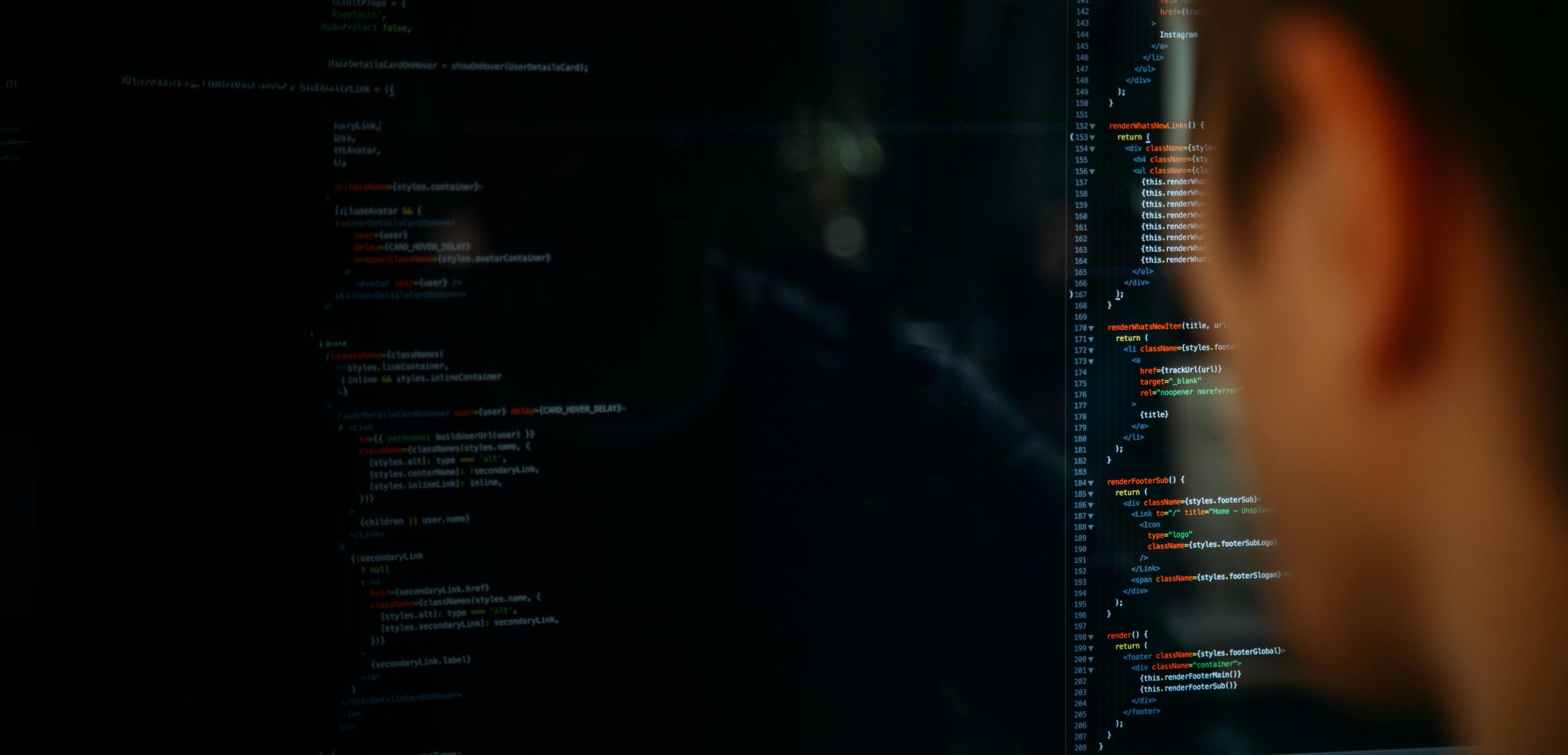 A person intently gazes at a computer screen displaying lines of code.
