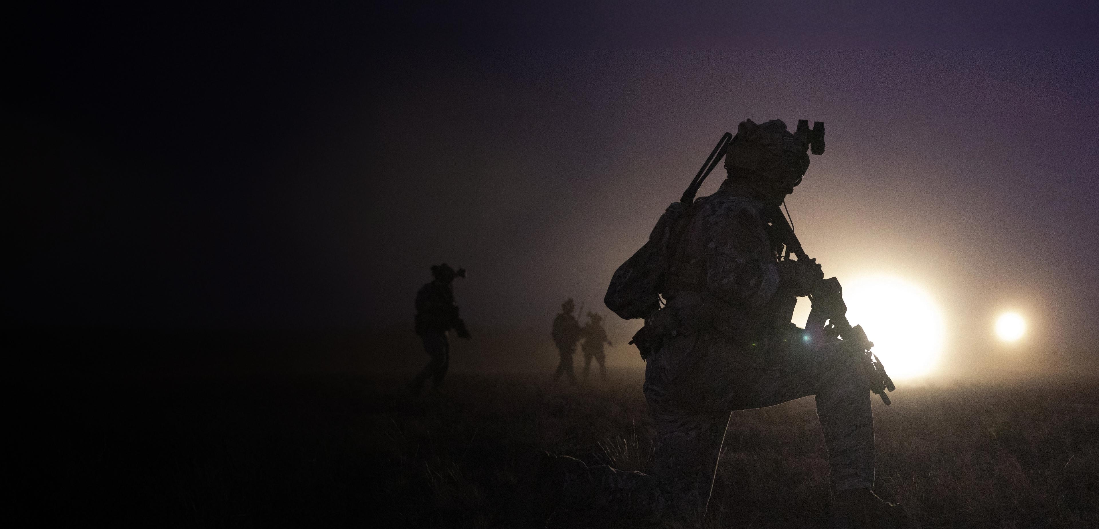 A soldier walks through darkness.