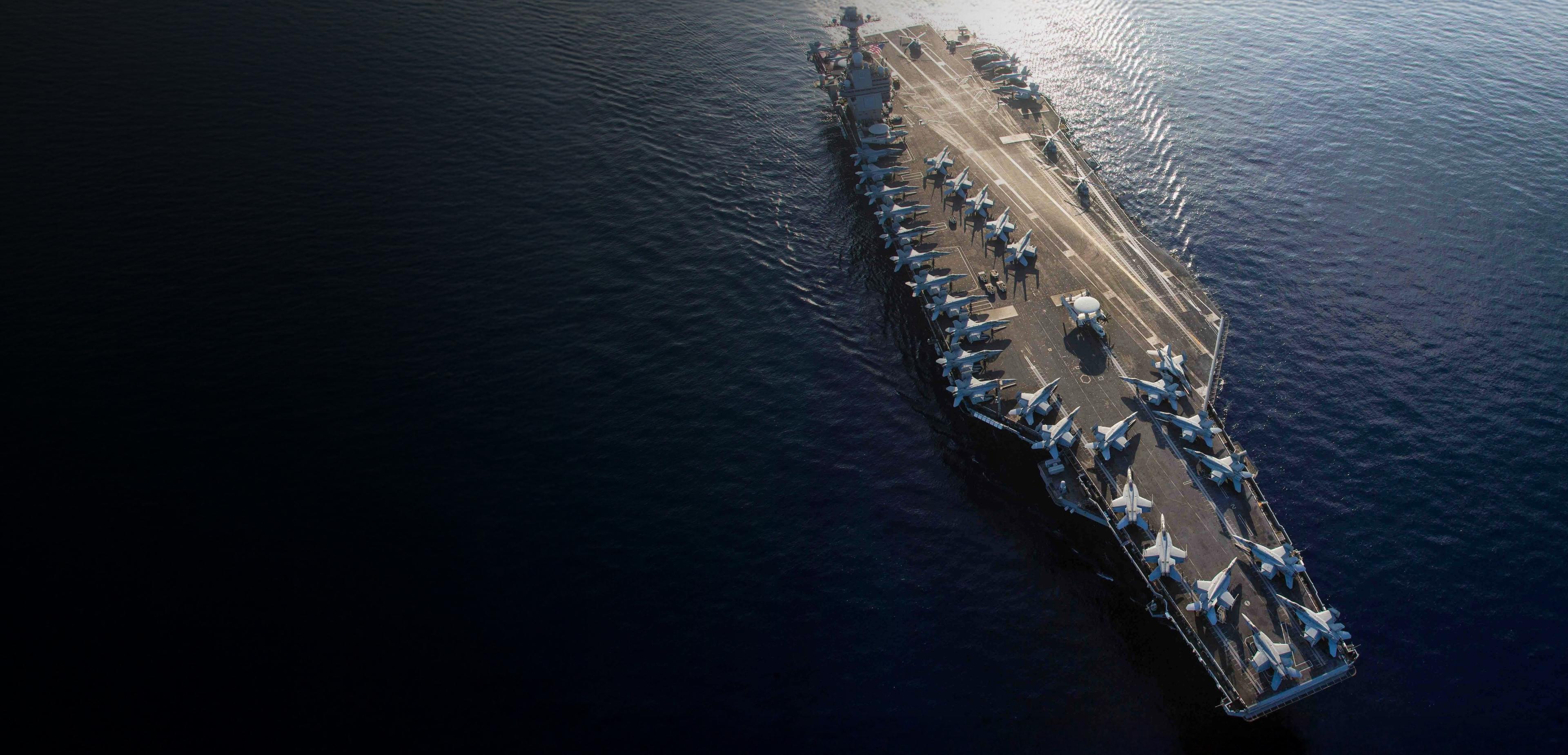 Aerial view of the USS CVN-76 aircraft carrier, showcasing its deck and surrounding water.