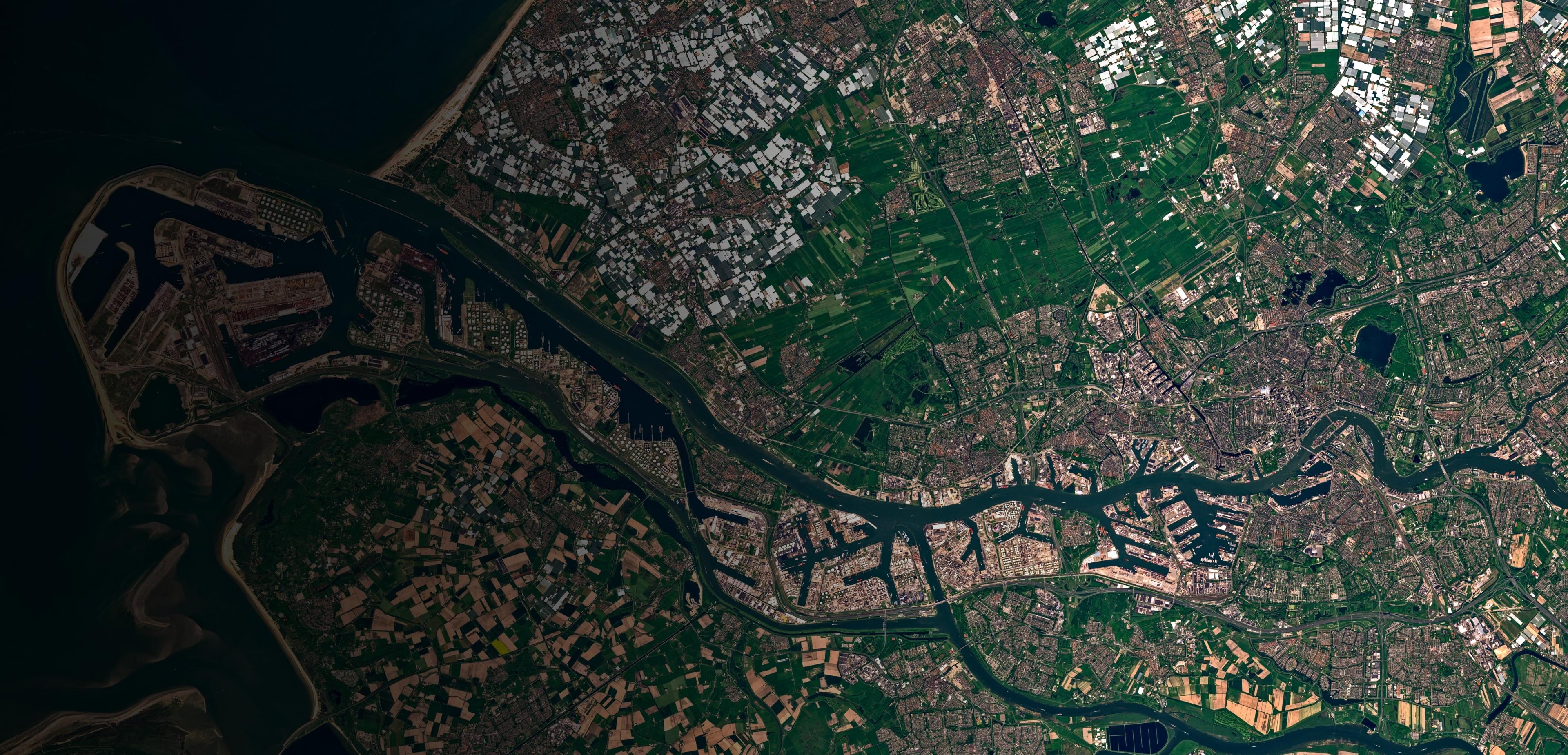 Aerial view showcasing a winding river surrounded by lush green land under a clear blue sky.