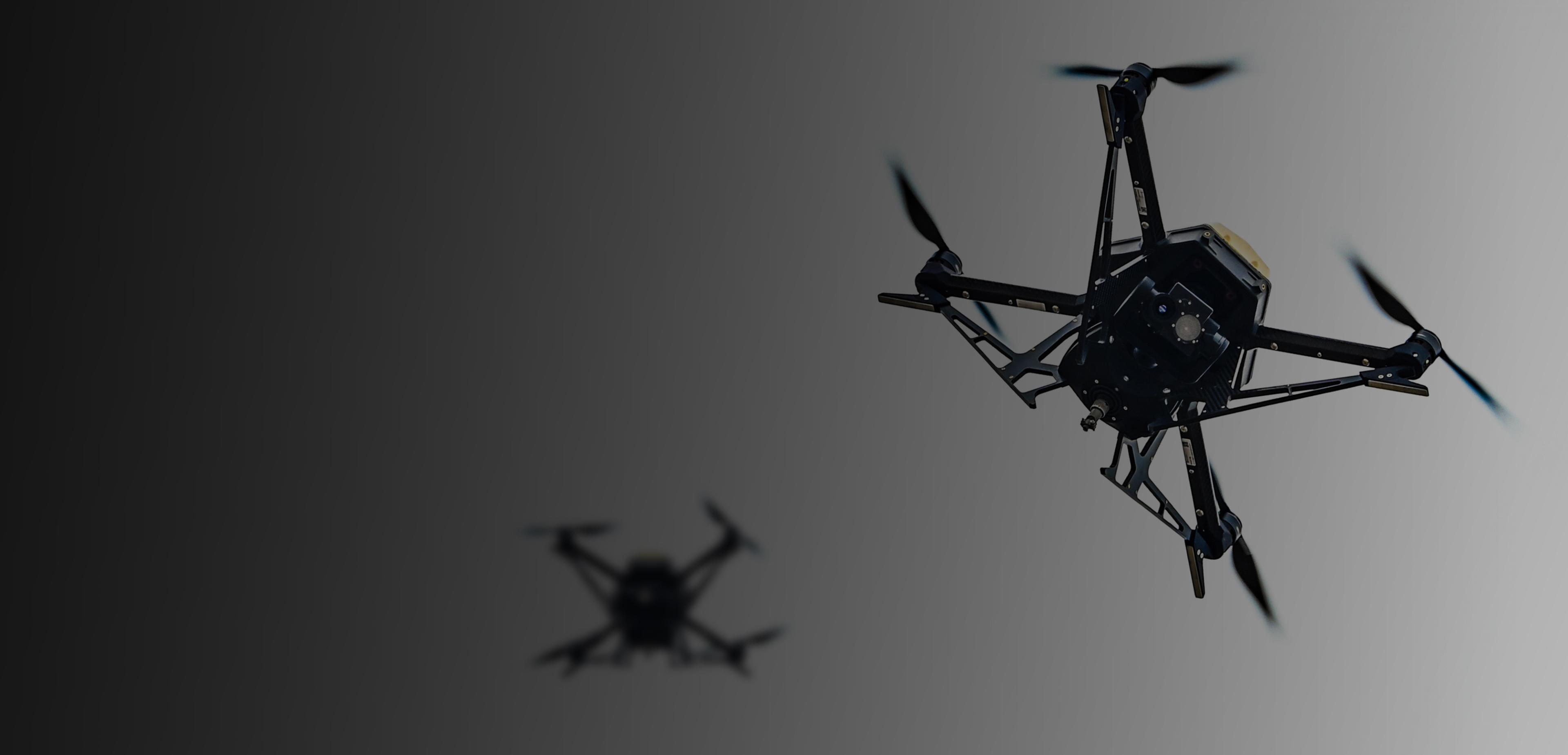 A black and white image featuring two small drones positioned side by side against a neutral background.